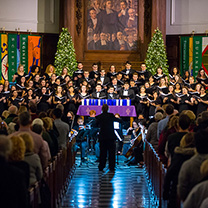 Singers in chapel with Christmas trees behind them